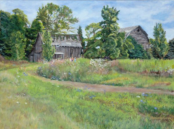 Faded gray barn surrounded by flowers and trees